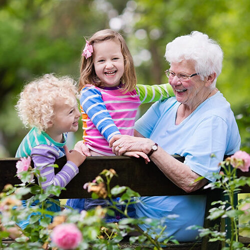 grandmother sitting in the garden with two young granddaughters