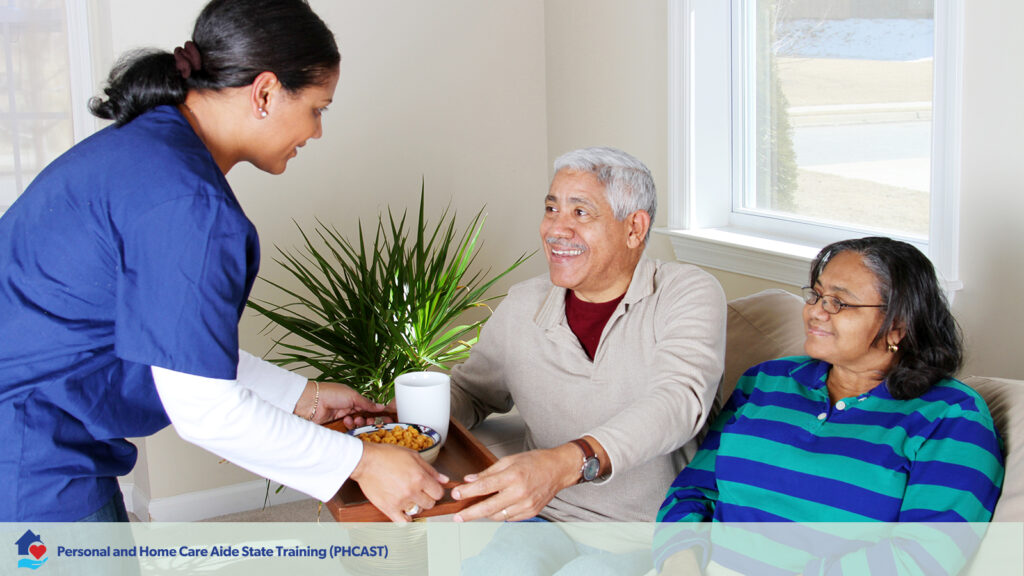 home care aid offers an older couple a tray with lunch