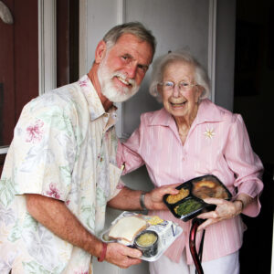 volunteer delivers a meal to a woman at home